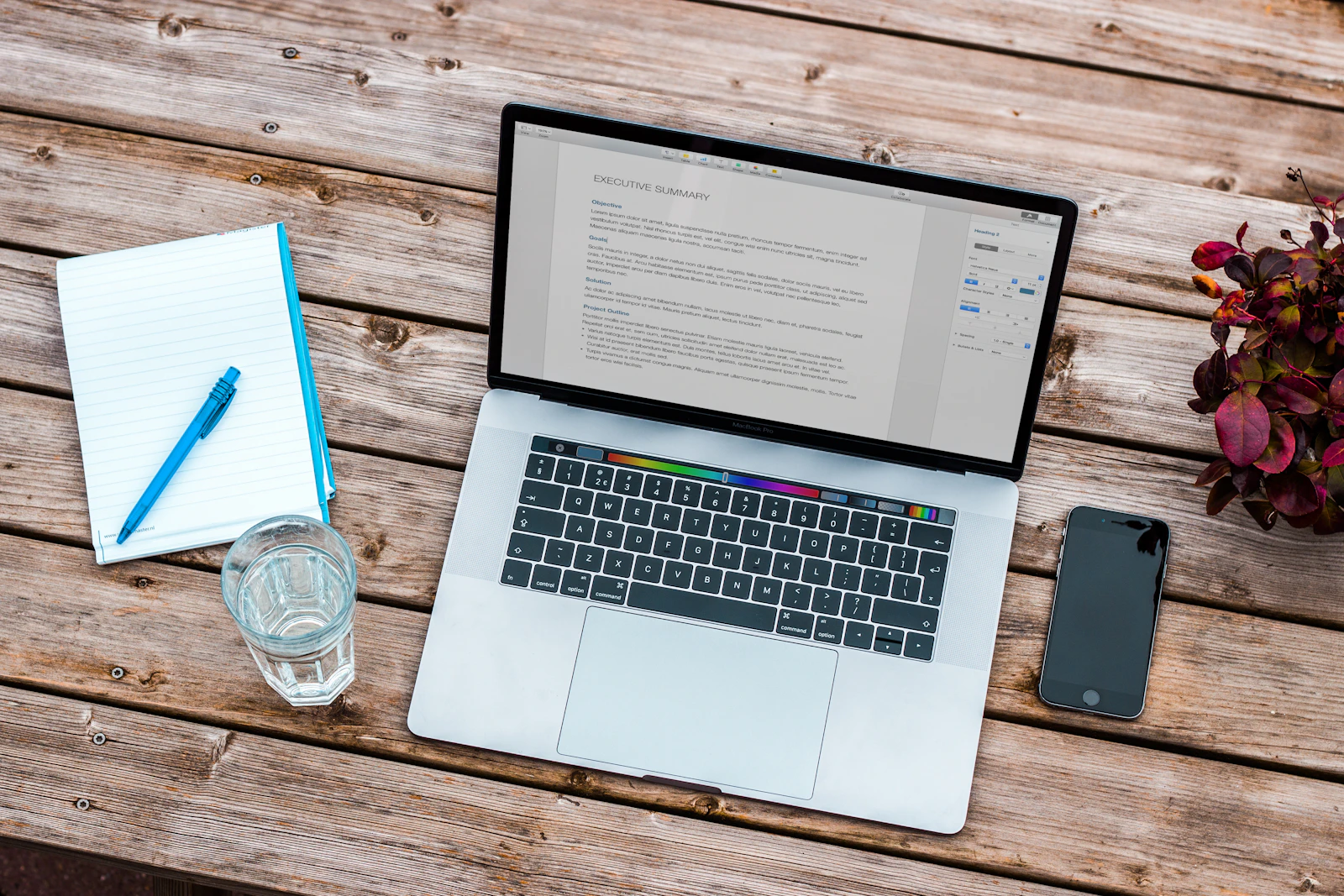 Laptop, Notizblock und Stift auf einem Holztisch